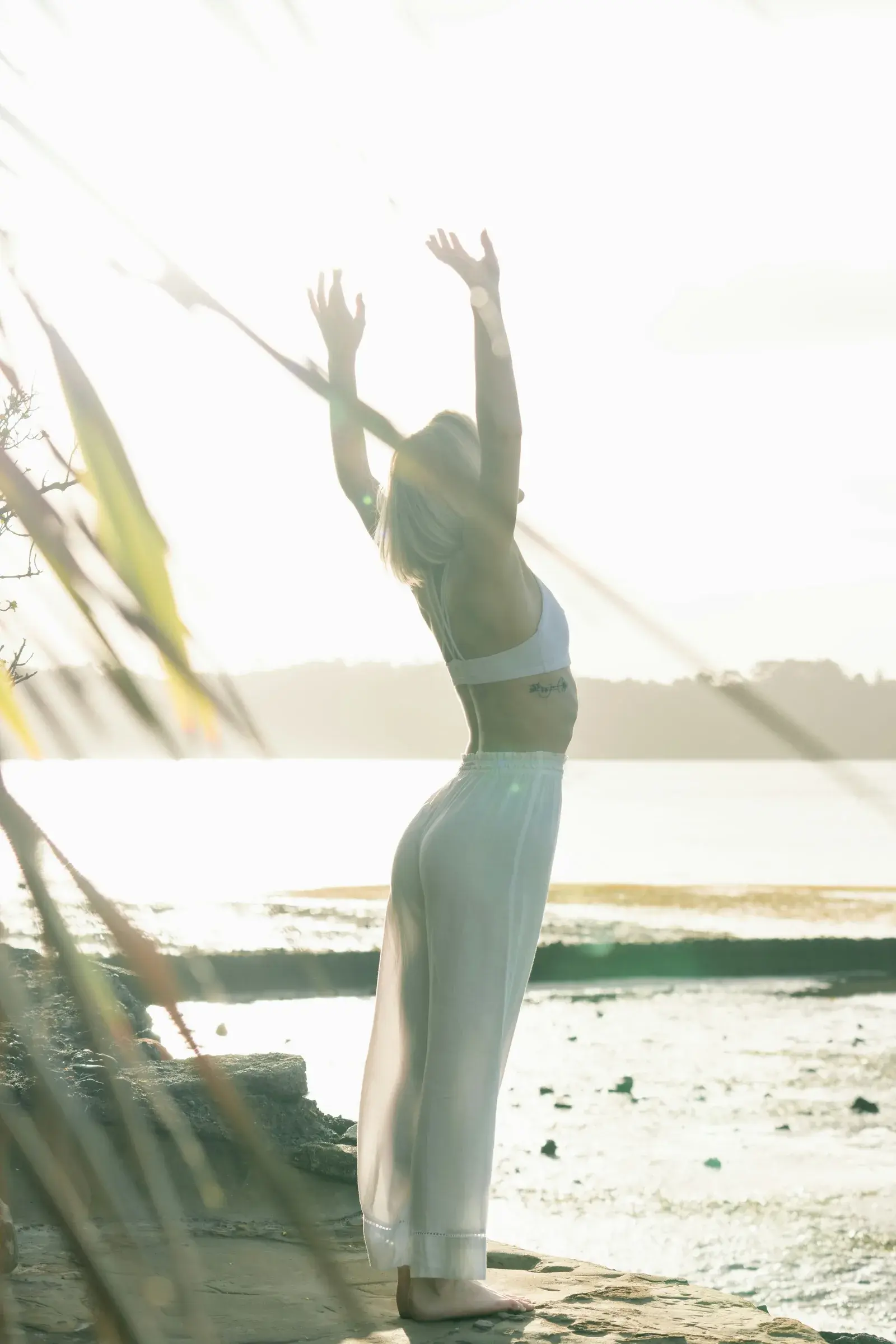 Woman standing and reaching high on a waterfront